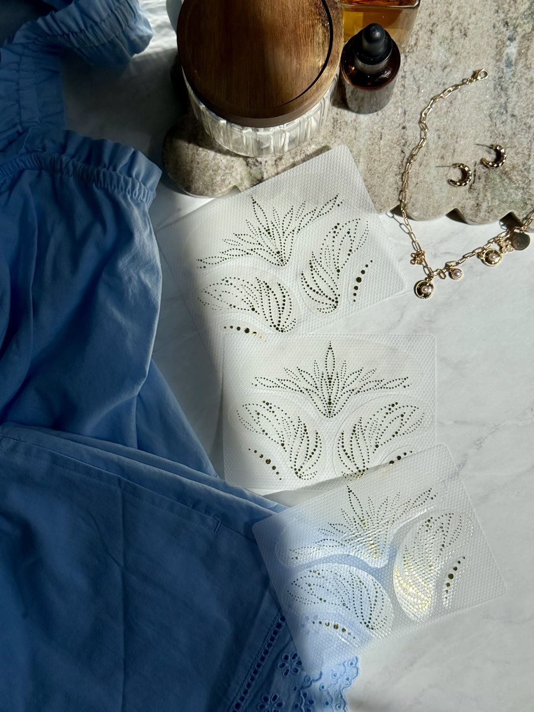 Complexion Tape sheets in a flat lay with gold jewelry